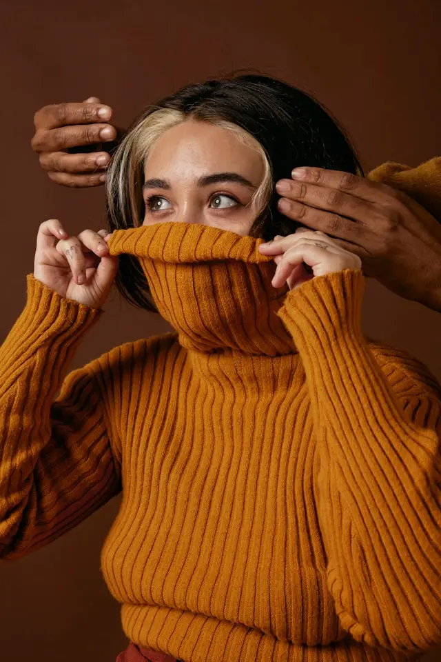 a woman in a turtle neck sweater covering her face i need of trauma and anxiety counseling.